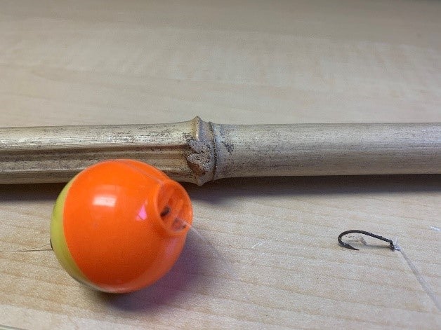 Cane pole with small metal hook and round plastic bobber. 